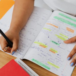 A person writing and highlighting notes in a graph notebook. Ideal for education and productivity themes.