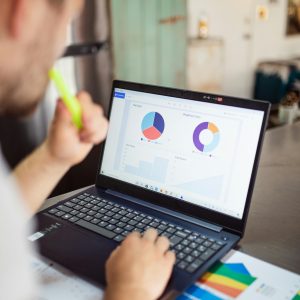 Focused adult analyzing charts and graphs on a laptop for business insights.