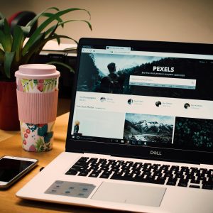 A tidy desk setting with a laptop showing a stock photo website and a smartphone.